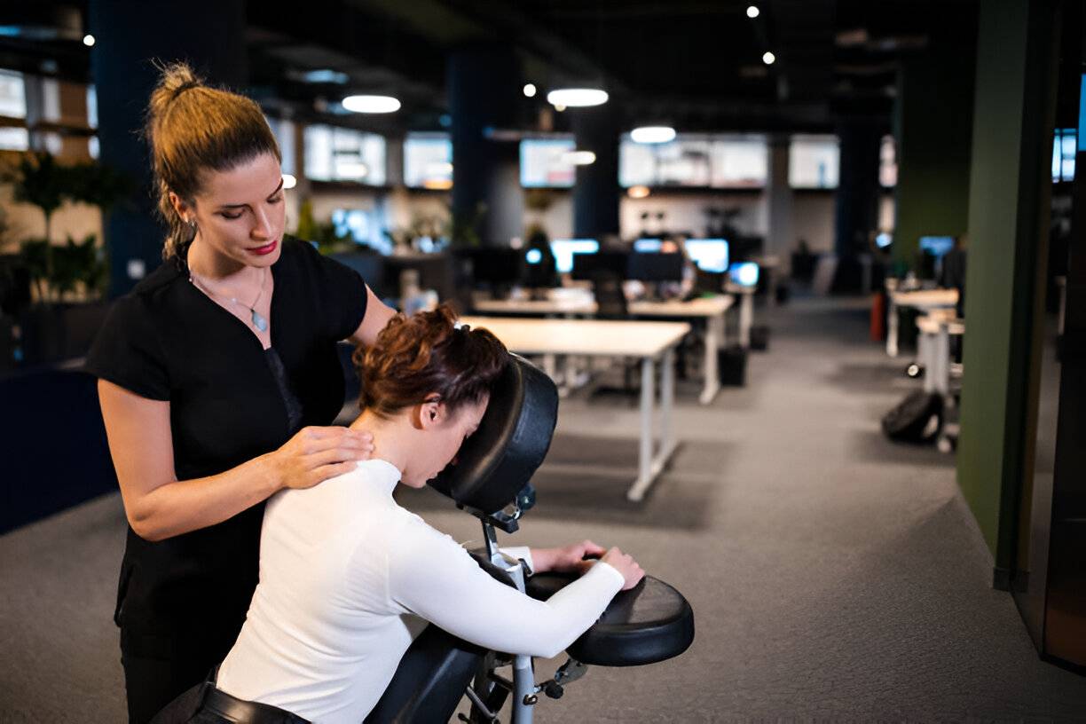 Female massage therapist giving businesswoman massage for her back and neck pain,